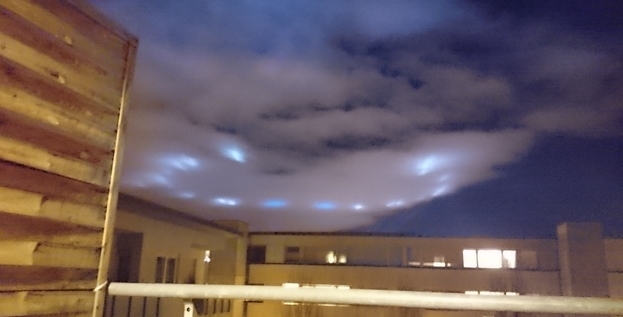 Stuttgart 2015 - Lichter eines Skybeamers Am bewölkten Himmel ein Kreis aus bläulich erscheinenden ovalen Lichtern.
