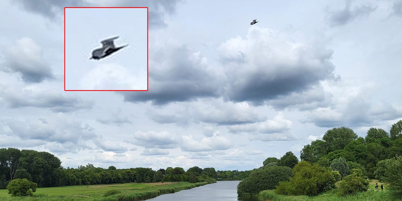 Rendsburg 2024 - von Kamera-KI verfälschter Vogel? Längliches dunkles Objekt am teilbewölkten Himmel, das in sich gebogen erscheint und zwei vogelartige Flügel aufweist.