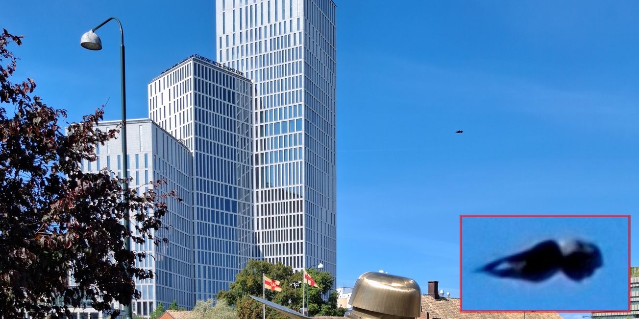Malmö 2024 - Objekt bisher ungeklärt Neben einigen Hochhäusern befindet sich am blauen Himmel ein schwarz erscheinendes Objekt, das einer waagerechten Qualle ähnelt.