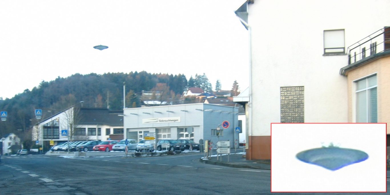 Puderbach 2005 - Straßenlaterne Eine fliegende Untertasse am hellen Himmel, die scheinbar über einer Straßenkreuzung schwebt.