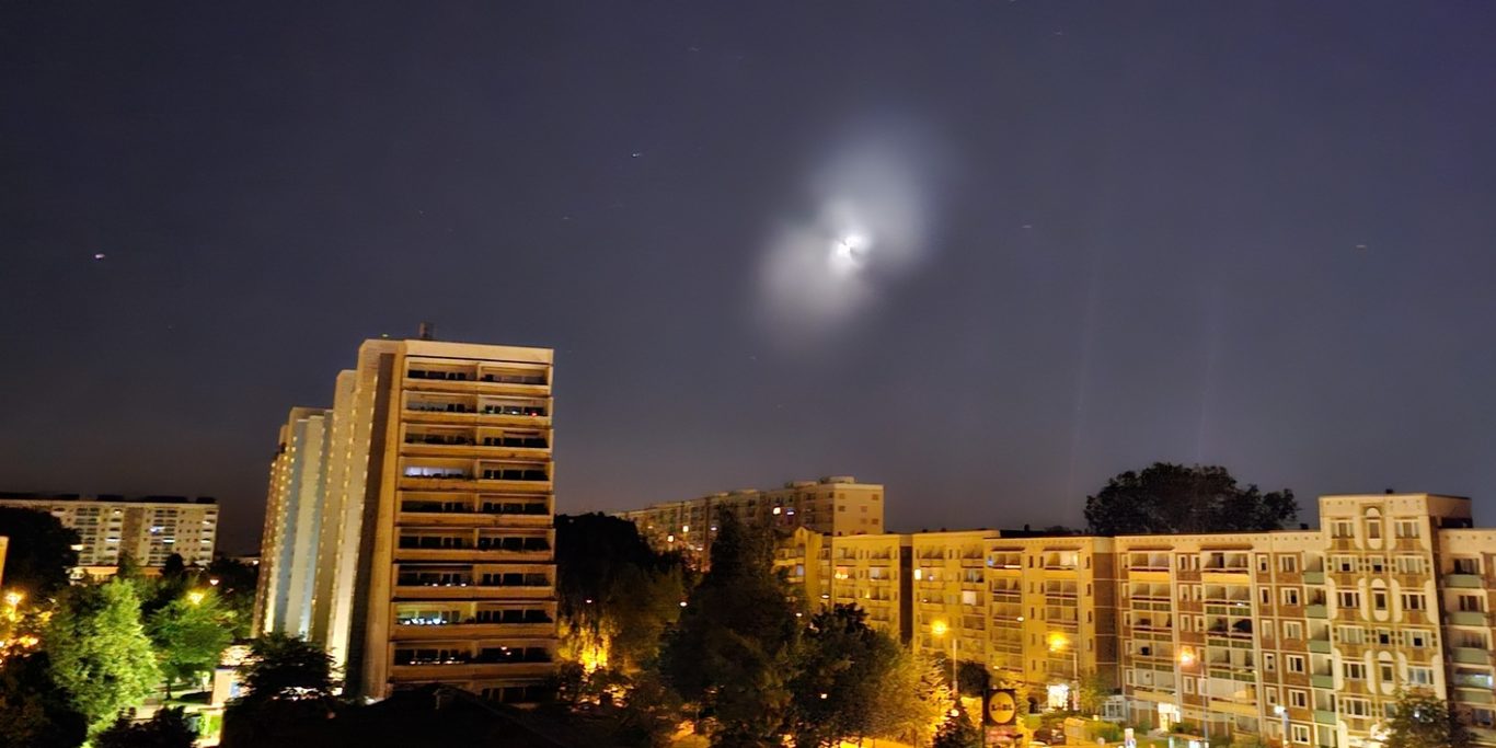 Rostock 2024 - Treibstoffausstoß einer Rakete Lichterscheinung am dunklen Himmel, die außen aus zwei diffusen Bereichen und innen aus einem hellen Kern besteht.